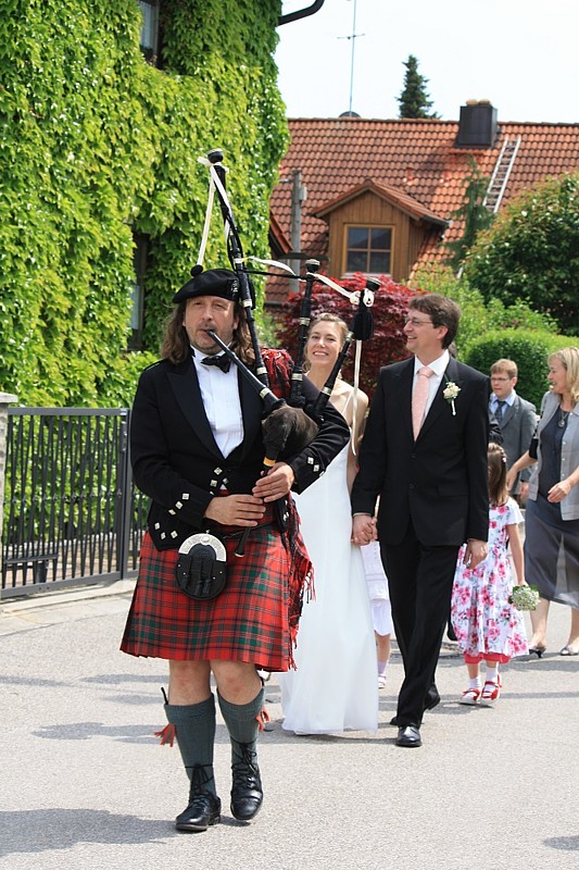 Quest spielt Highland-Bagpipes während er vor einem Brautpaar marschiert